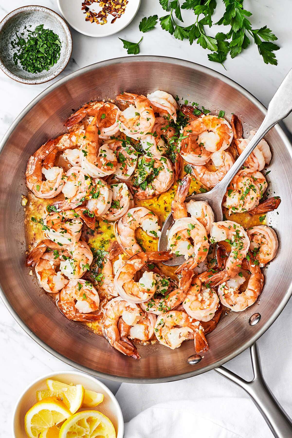 Shrimp scampi in a large pan with a spoon