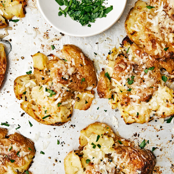 Smashed potatoes on a sheet pan with parsley sprinkled on top.