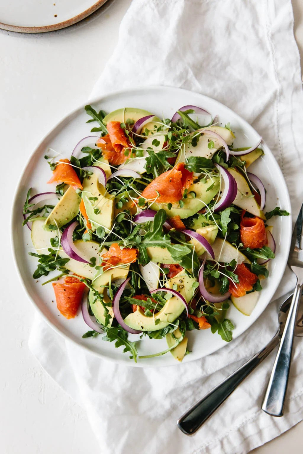An easy and delicious arugula salad recipe made with baby arugula, smoked salmon, avocado, pear and red onion.