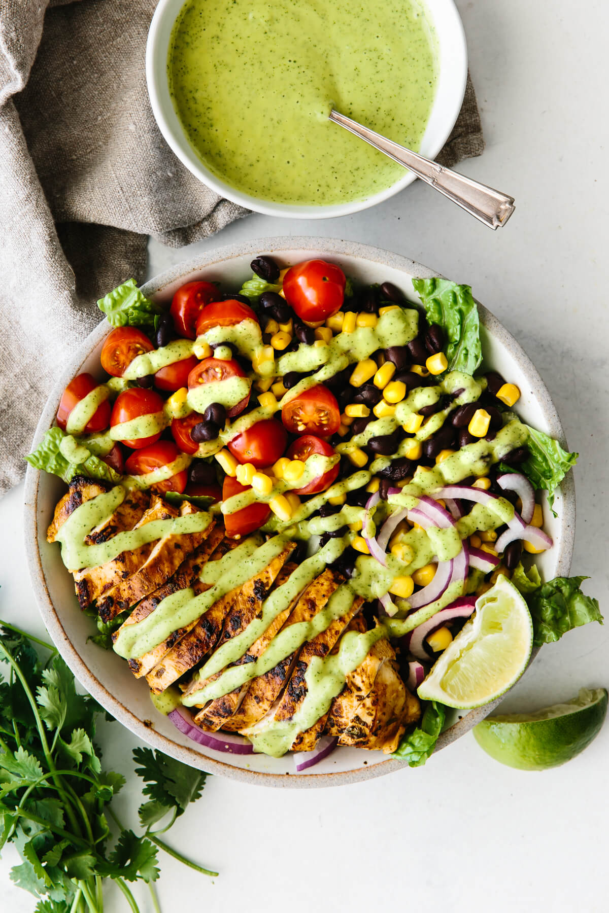 Southwest chicken salad in a white bowl next to a small bowl of avocado dressing.