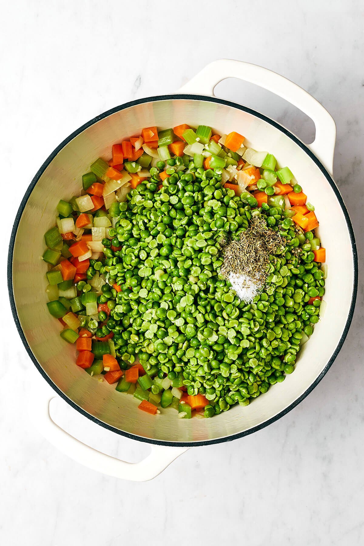 Adding split pea soup ingredients into a pot