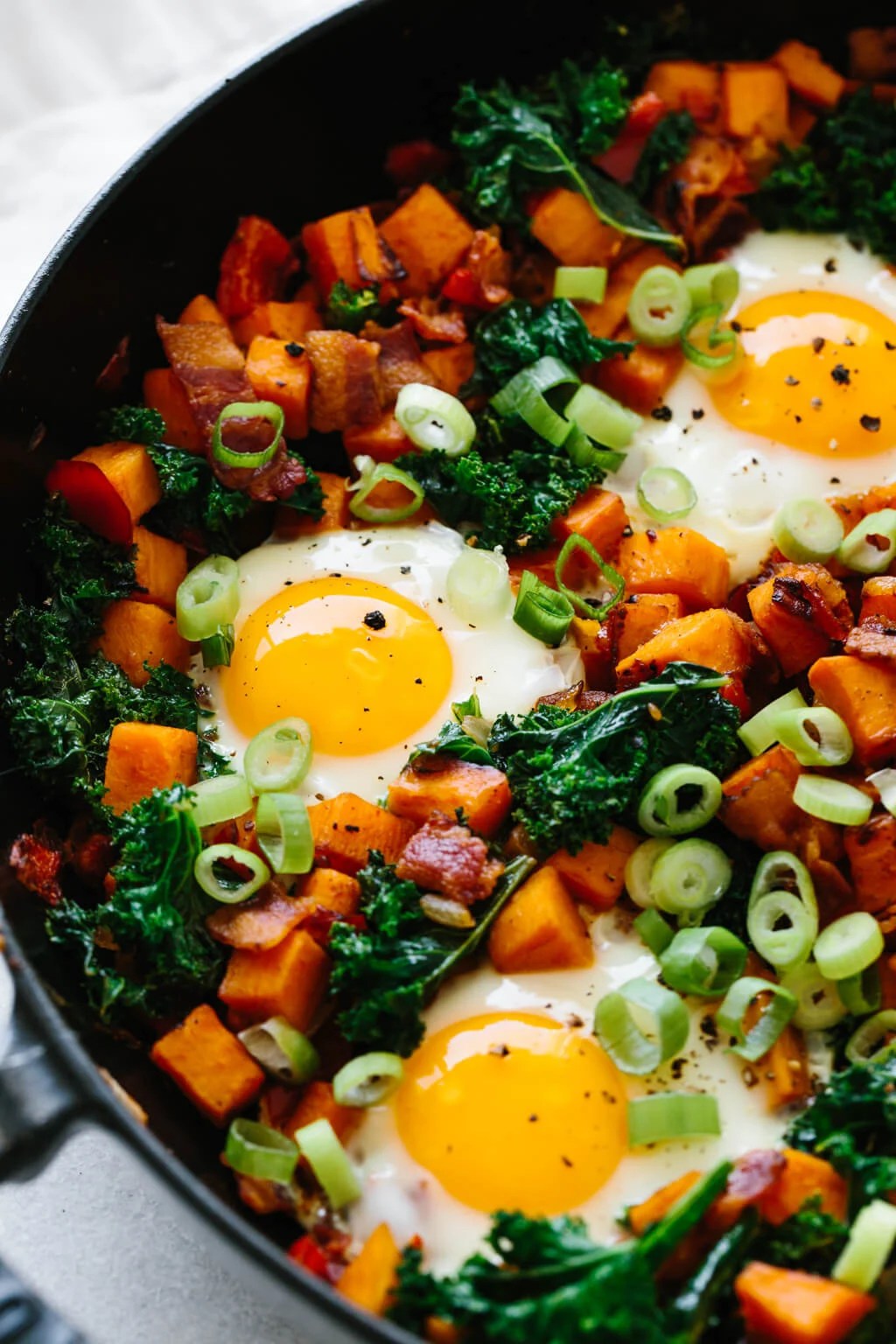 Eggs nestled between vegetables in a sweet potato breakfast hash recipe.