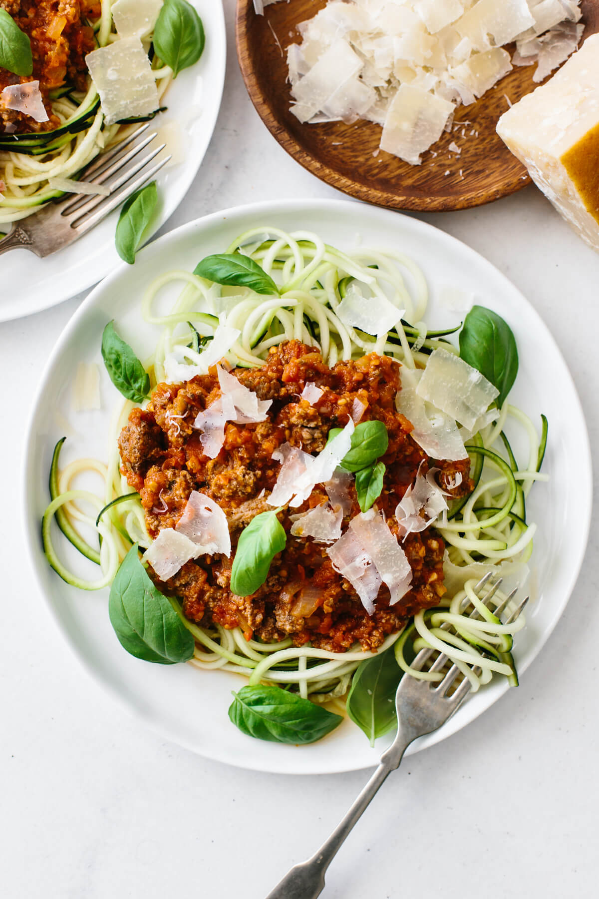 A plate of zucchini noodles topped with bolognese sauce, fresh parmesan and basil.